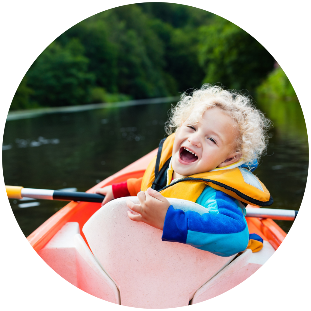 Photo of a really happy kid smiling im a kayak on the lake