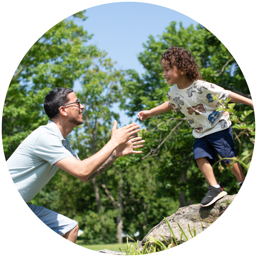 Dad and son playing outside - the son is jumping from a log into his dad's arms